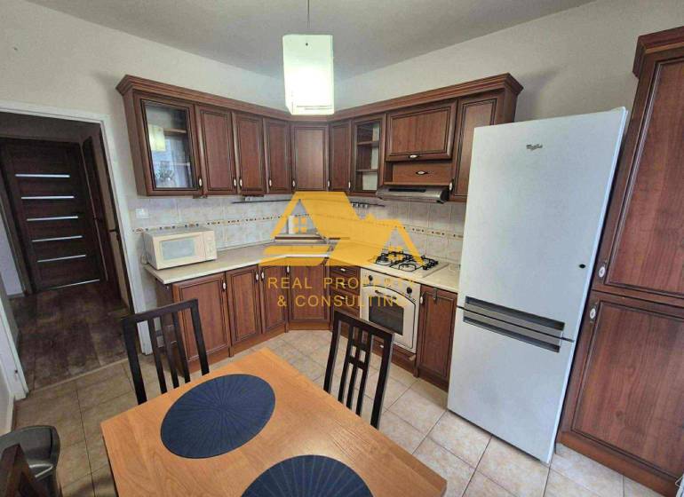 Kuchyně s tmavým dřevěným dekorem, sporákem a lednicí ve 3-pokojovém bytě.