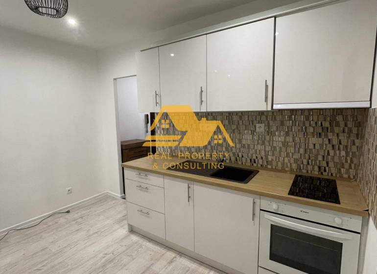 Kuchyně v 1-pokojovém bytě se světlou linkou a podlahou s dřevěným dekorem.