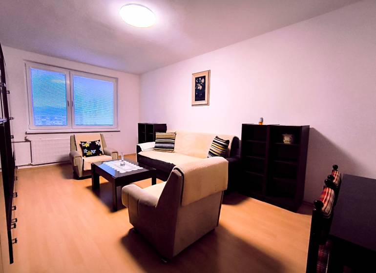 Obývací pokoj v 2-pokojovém bytě s minimalistickým nábytkem a podlahou s dřevěným dekorem.