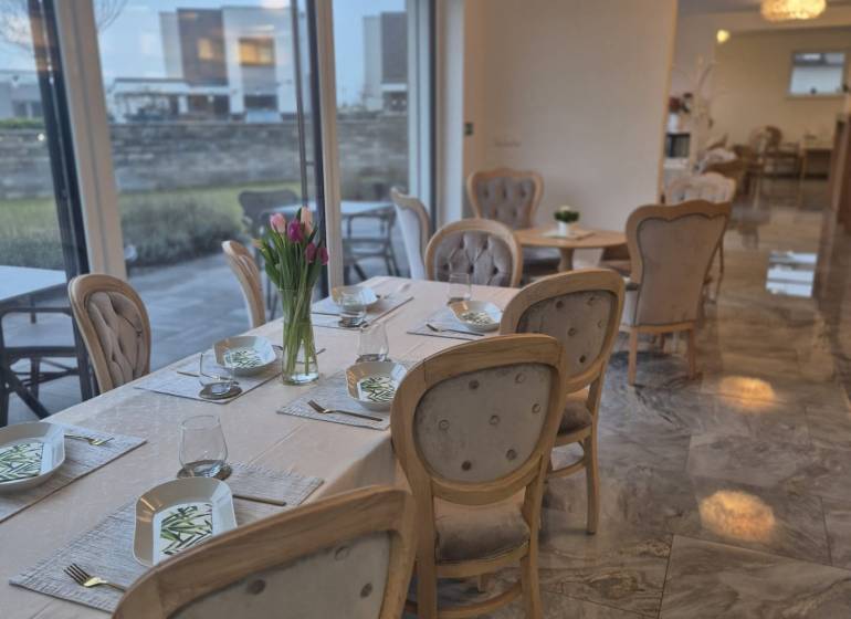 Útulné gastro prostory s elegantním prostíráním, květinami a velkými okny.