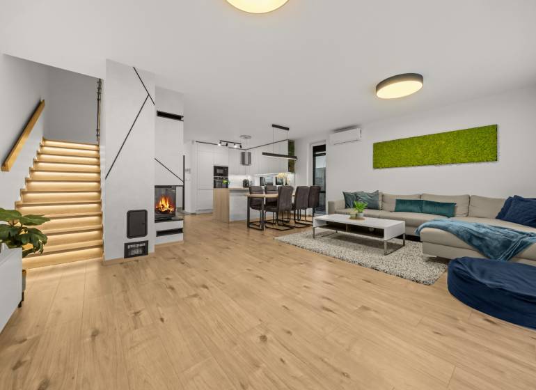 Obývací pokoj 4pokojového bytu s podlahou s dřevěným dekorem, krbem a moderním schodištěm.