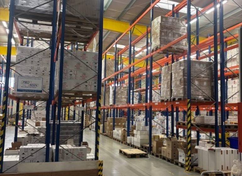 Regály ve skladech a halách plné uskladněného zboží na paletách.