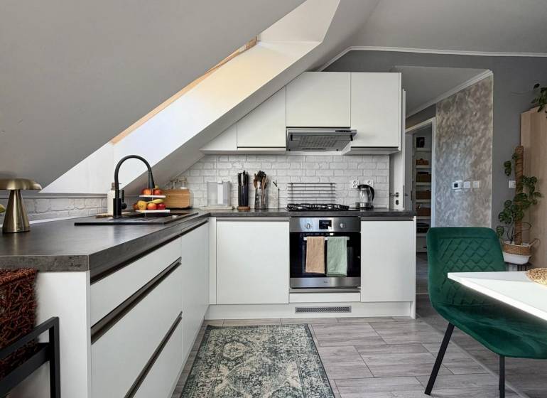 Kuchyně v 2-pokojovém bytě se šikmým stropem a podlahou s dřevěným dekorem.