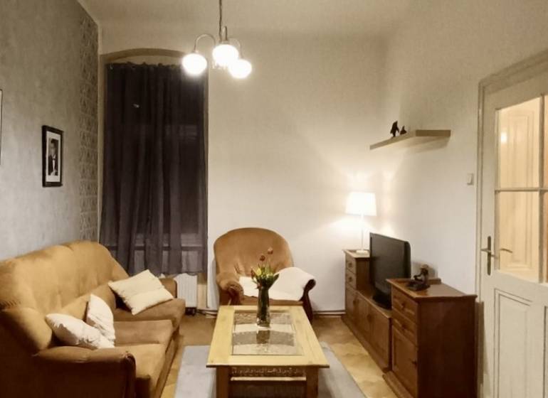 Obývací pokoj v 3-pokojovém bytě s podlahou s dřevěným dekorem, útulné posezení a osvětlení.