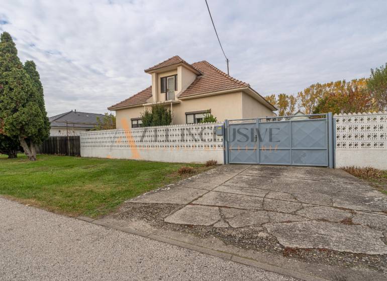 Rodinný dům ve Velkých Dvorníkách s velkou zahradou, stromy a betonovým chodníkem.