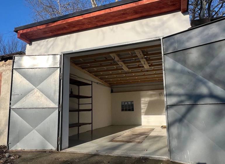 Otevřená garáž na Agátové v Bratislavě - Dúbravce s jednoduchým interiérem a regálem.