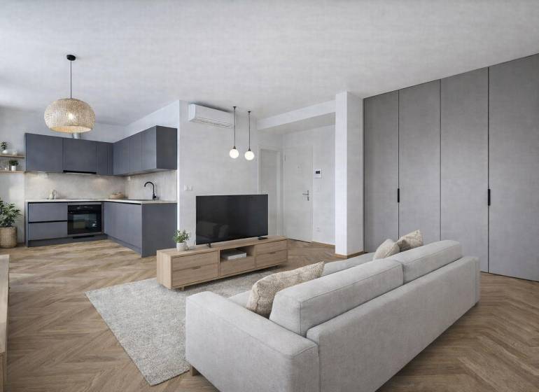 Kuchyně v 1-pokojovém bytě s podlahou s dřevěným dekorem a šedými skříňkami.