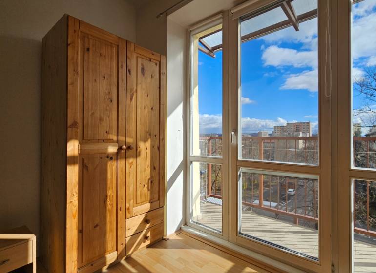 Slunný interiér 2pokojového bytu s podlahou s dřevěným dekorem a dřevěnou skříní.