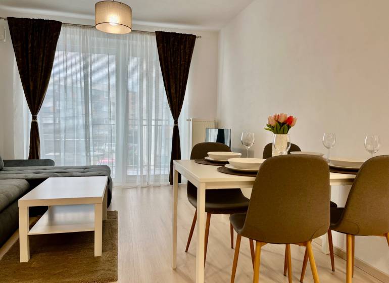 2-pokojový byt s podlahou s dřevěným dekorem, jídelním stolem a pohovkou.