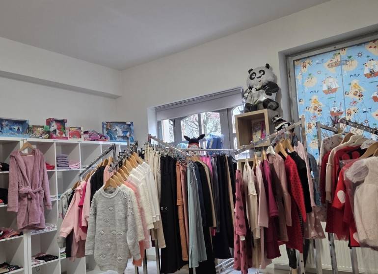 Obchod s oblečením a hračkami s regály a policemi ve Zvláštních nemovitostech.