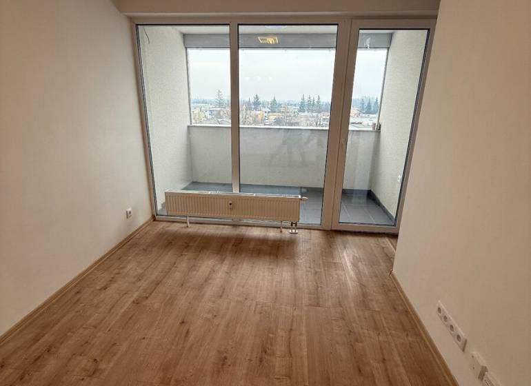 Obývací pokoj v 1-pokojovém bytě s podlahou s dřevěným dekorem a velkými okny.