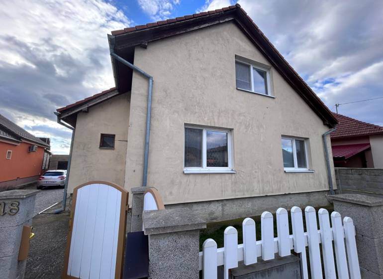 Rodinný dům v Zbehoch se šikmou střechou, plotem a příjezdovou cestou.