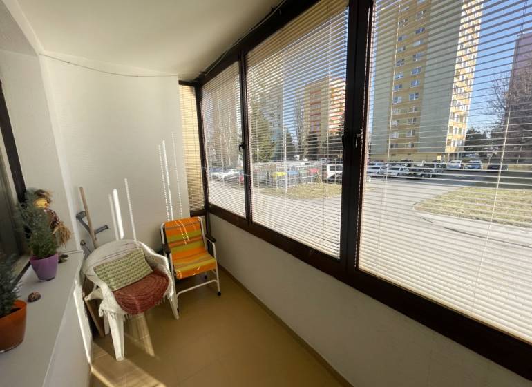 Zasklená lodžie ve 3-pokojovém bytě s výhledem do ulice, vybavená křesly.
