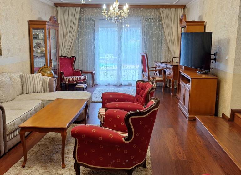 Obývací pokoj v rodinném domě s červenými křesly a podlahou s dřevěným dekorem.