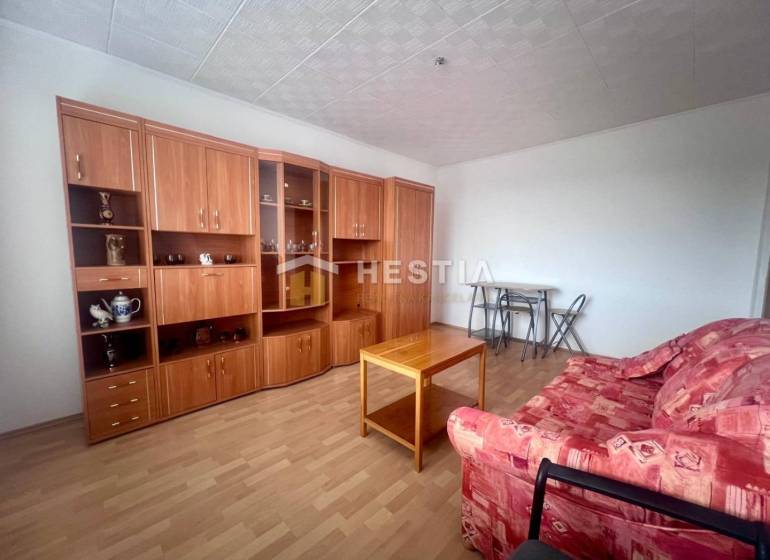 Obývací pokoj v 3-pokojovém bytě s červenou sedačkou a dřevěnou obývací stěnou.