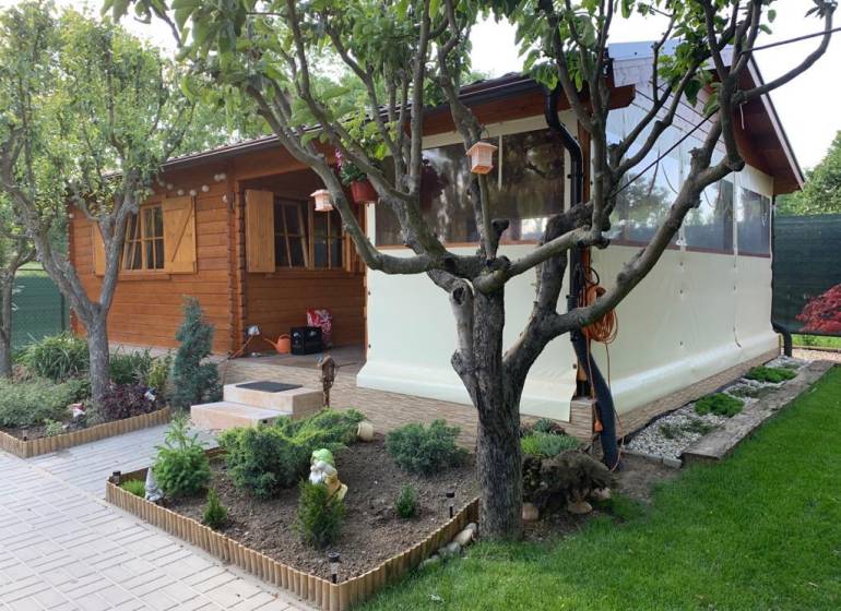 Dřevěný zahradní domek obklopený zelení v zahradách Dolních Krškán v Nitře.