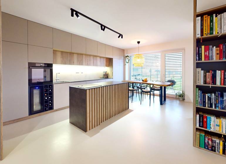 Otevřená kuchyně s jídelním stolem a knihovničkou v rodinném domě.