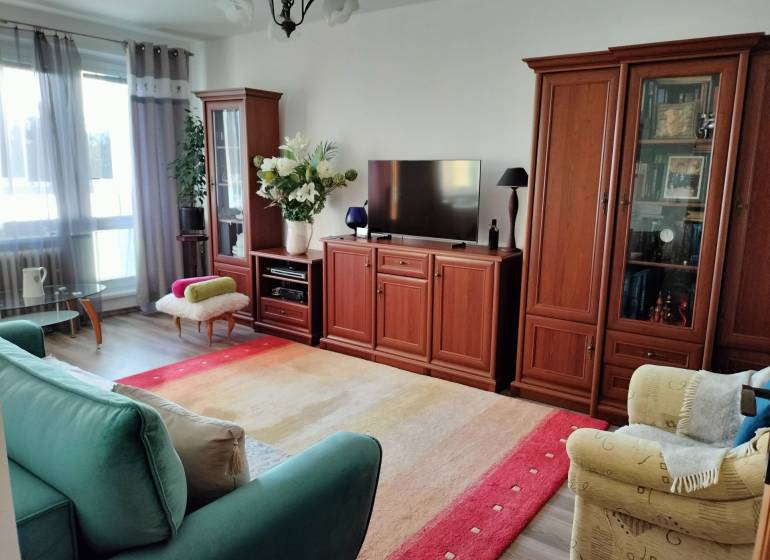 Obývací pokoj v 2pokojovém bytě s podlahou s dřevěným dekorem a pohodlným nábytkem.