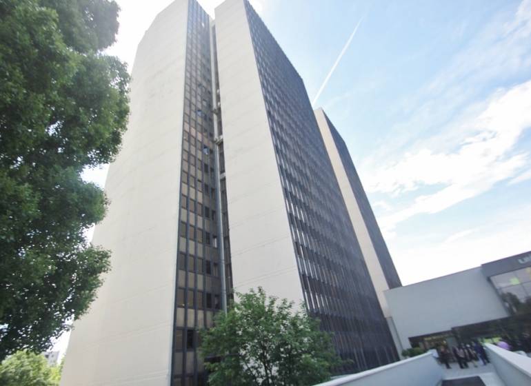 Výšková budova kanceláří na Kutlíkově ulici v Bratislavě - Lúky, částečně obklopená zelení.