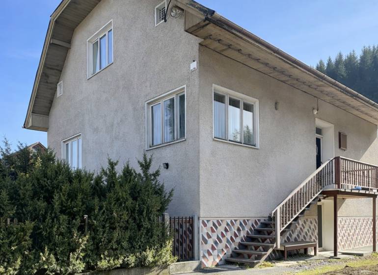 Rodinný dům v Terchové s velkými okny, schodištěm a udržovanou předzahrádkou.