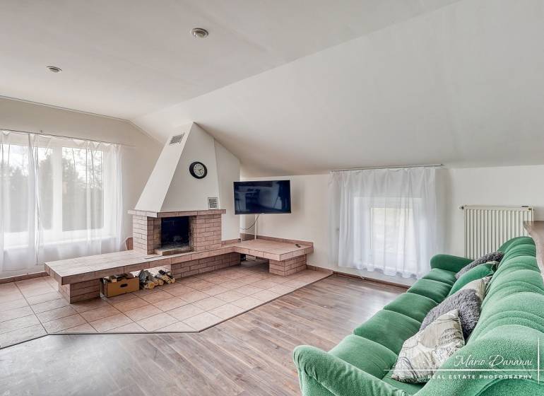 Obývací pokoj s krbem, zelenou pohovkou a podlahou s dřevěným dekorem v rodinném domě.