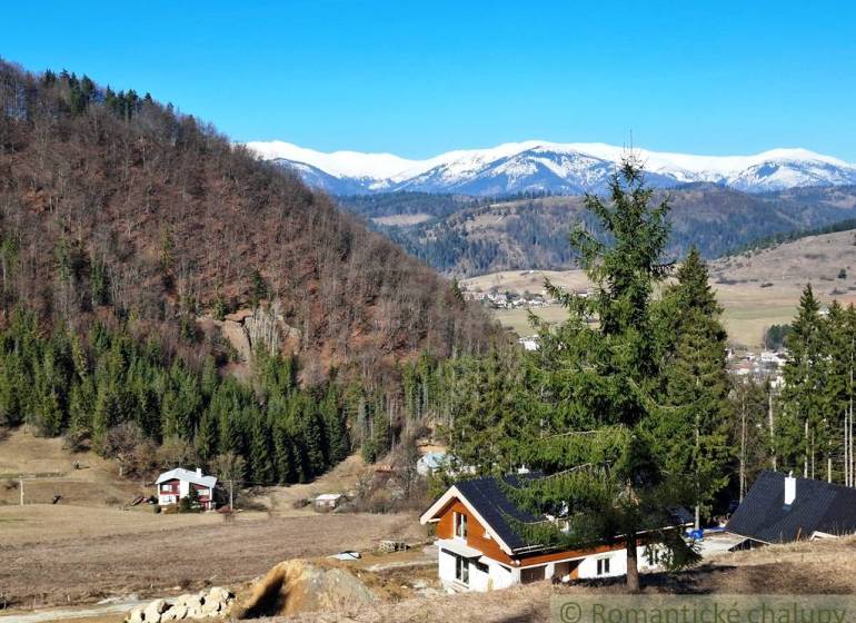 Sněhem pokryté hory a chalupy obklopené lesy a zemědělskými pozemky u Hronce.