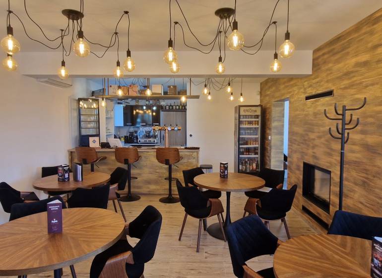 Gastro prostory s podlahou s dřevěným dekorem a závěsnými žárovkami.