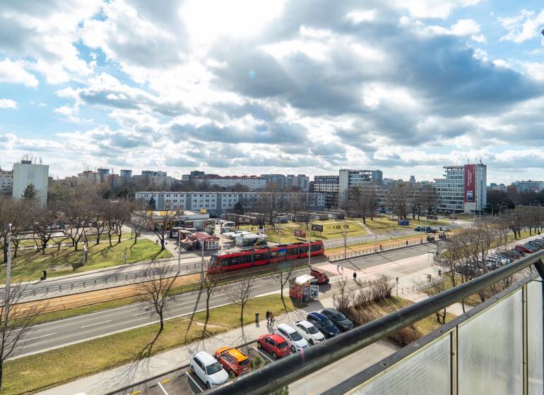 Výhľad na rušnú ulicu v Bratislave - Ružinov, Súmračná, s električkou a parkom.