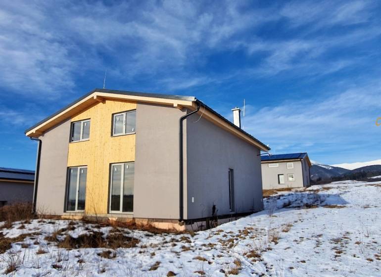 Chata v Dolní Lehotě s dřevěným obkladem, zasněžená krajina a hory na obzoru.