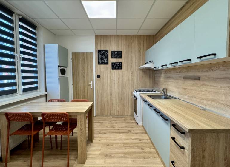 Kuchyně ve 3-pokojovém bytě s jídelním stolem a podlahou s dřevěným dekorem.