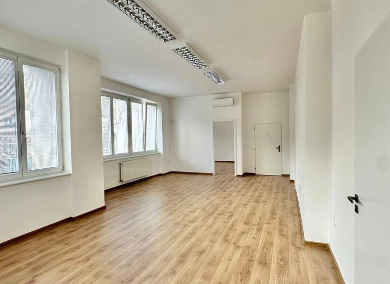 Kanceláře s podlahou s dřevěným dekorem, bílými stěnami a okny nabízejí jasný pracovní prostor.