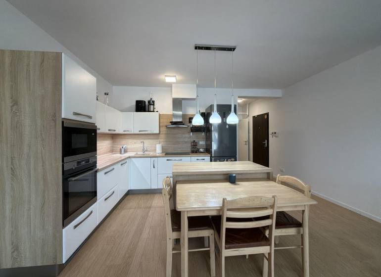 Kuchyně v 3-pokojovém bytě s podlahou s dřevěným dekorem a jídelním stolem.