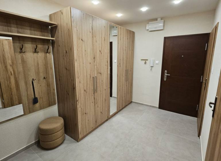 Chodba v 2-pokojovém bytě s nábytkem s dřevěným dekorem a vestavěným zrcadlem.