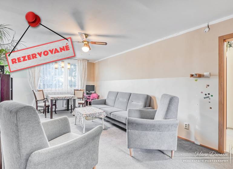 Obývací pokoj ve 4pokojovém bytě s pohodlnými křesly a jídelním koutem.