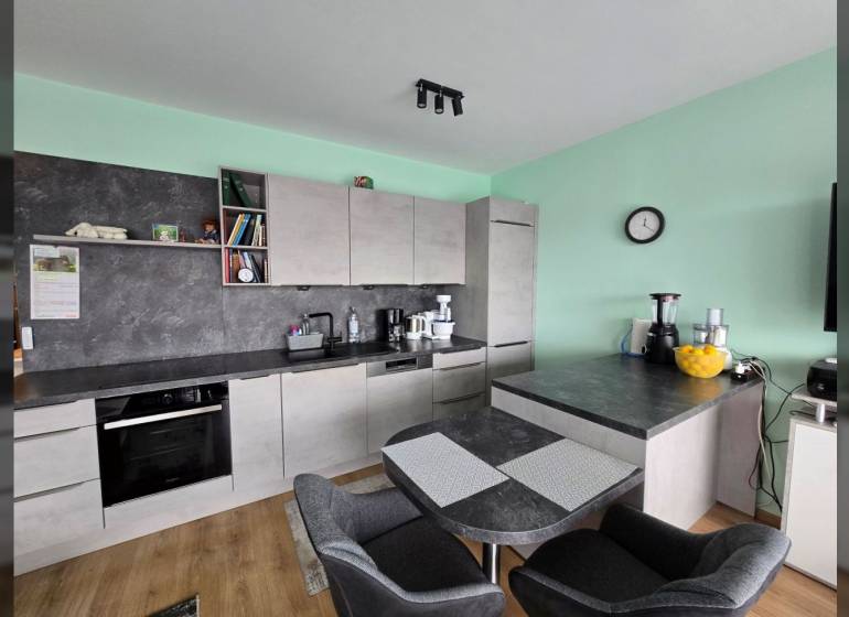 Kuchyně s jídelním stolem a podlahou s dřevěným dekorem v Rekreačním apartmánu.