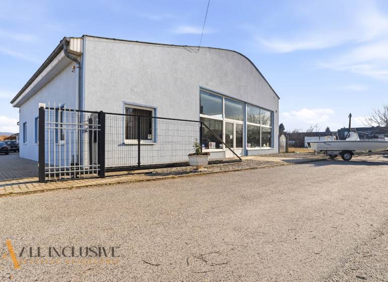 Obchodní prostory v Štúrově s šedou fasádou, parkováním a přístřeškem.