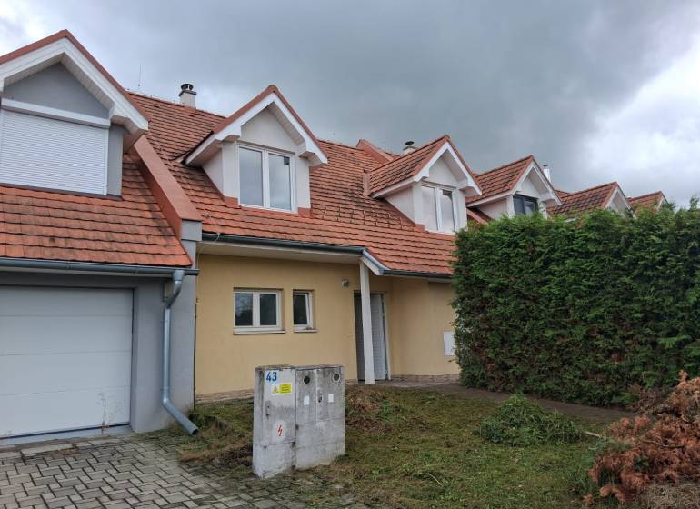 Rodinný dům v Ľubeli s červenou střechou, garáží a udržovanou zahradou.