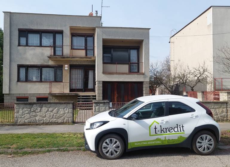 Rodinný dům ve Zlatých Moravcích se zaparkovaným autem realitní kanceláře před domem.