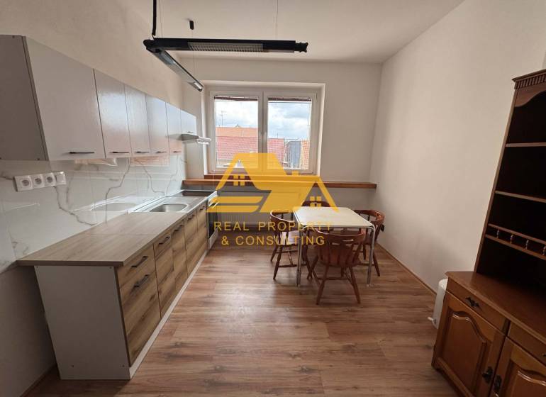 Kuchyně v 1-pokojovém bytě se stolem, židlemi a podlahou s dřevěným dekorem.