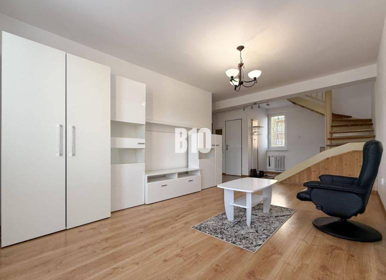 Obývací pokoj v rekreačním apartmánu s bílým nábytkem a podlahou s dřevěným dekorem.