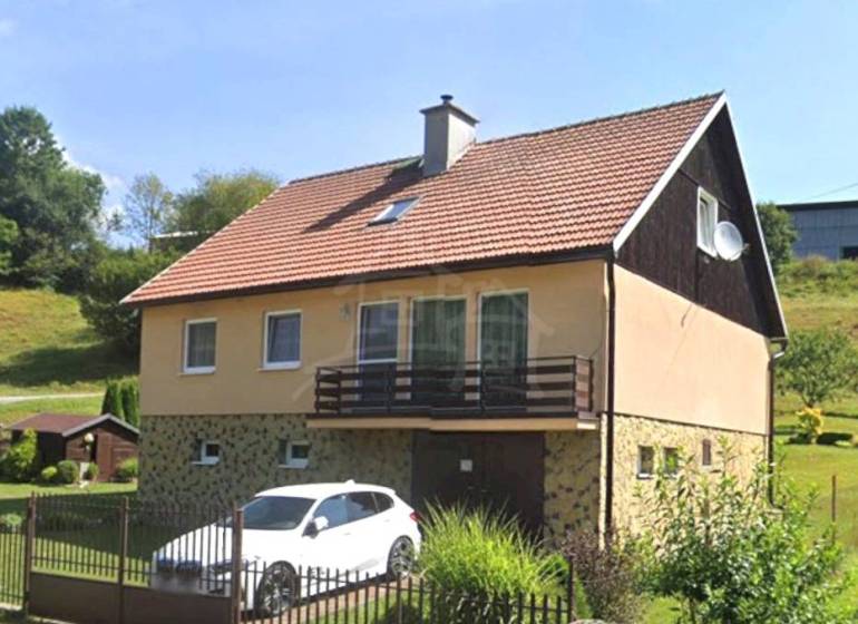 Rodinný dům v Liptovských Revúcích s garáží a zahradou na svažitém pozemku.