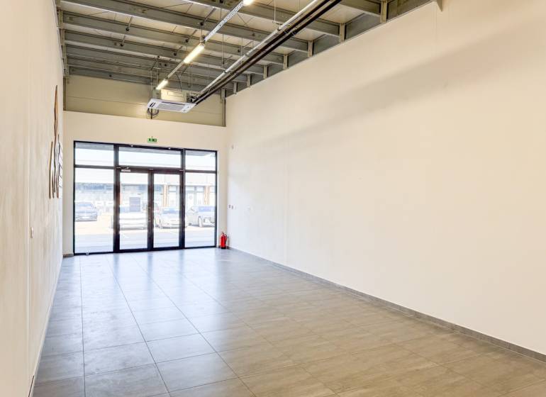 Prostorné obchodní prostory s dlažbou a velkými dveřmi.