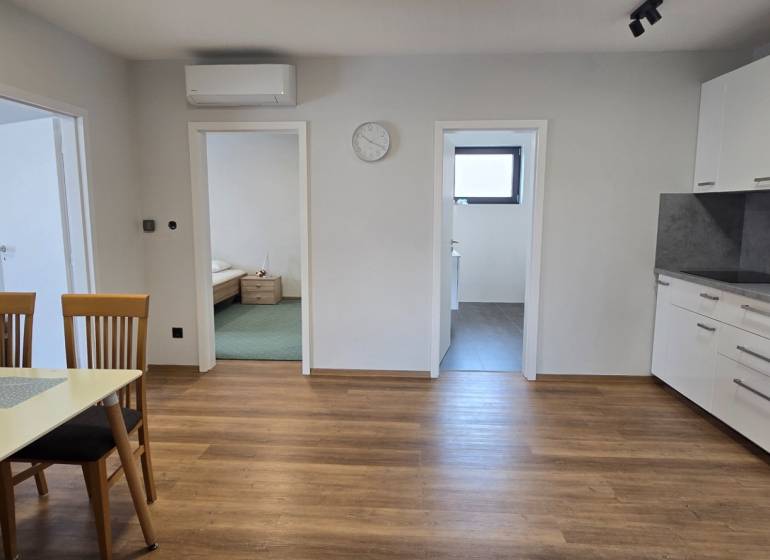 Kuchyně v 3pokojovém bytě s podlahou s dřevěným dekorem a jídelním stolem.