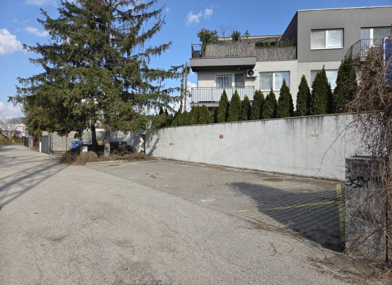 Garáže na Vavřínové ulici v Bratislavě - Ružinově s okolní zelení a domy.