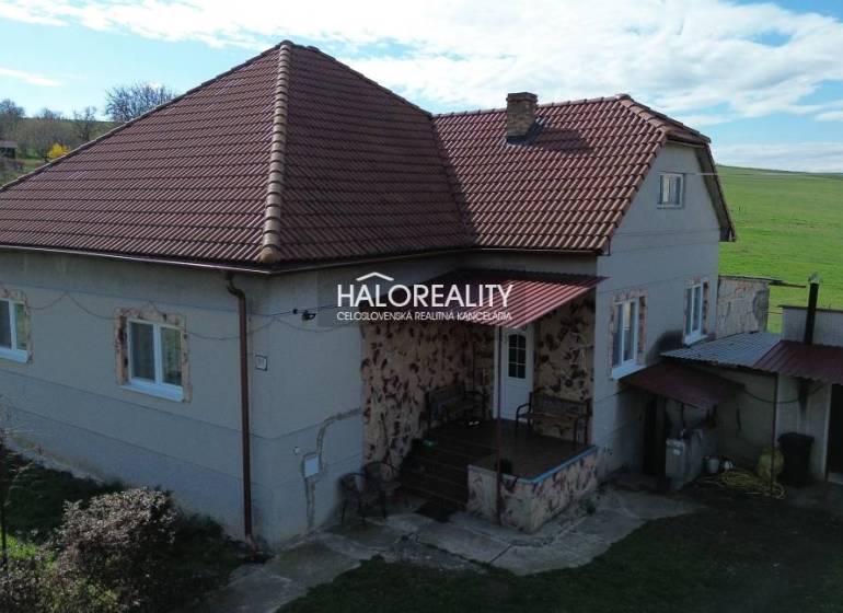 Rodinný dům v Rimavských Janovcích s červenou střechou a venkovským okolním prostředím.