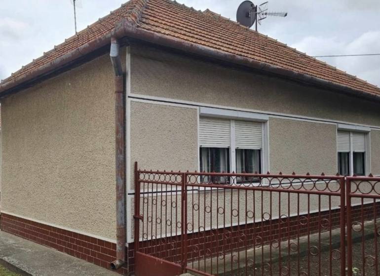 Rodinný dům v Radavě na Hlavní ulici s červenou střechou a bílými okenicemi.