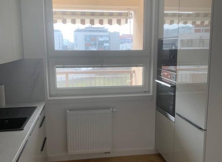 Kuchyně s podlahou s dřevěným dekorem v 2pokojovém bytě, má moderní spotřebiče.