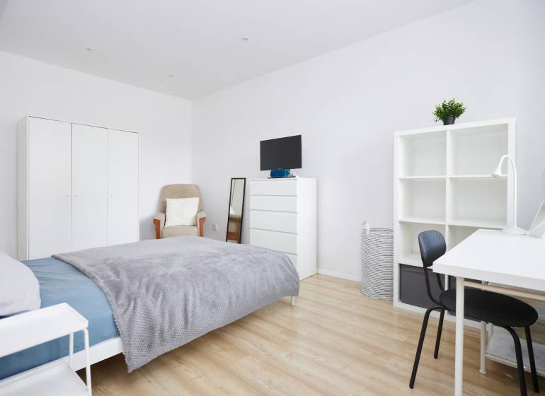 Ložnice v 2-pokojovém bytě s bílým nábytkem a podlahou s dřevěným dekorem.