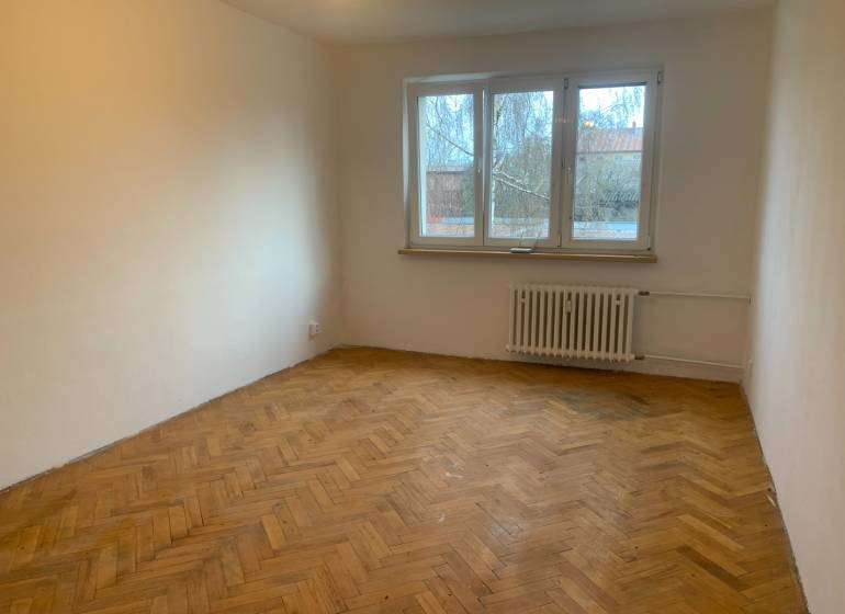 Pokoj v 2-pokojovém bytě s podlahou s dřevěným dekorem a velkým oknem.