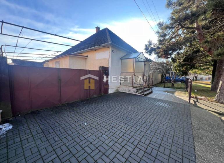 Rodinný dům se zahradou v Senici, velká vstupní brána, dlážděný dvůr, strom.